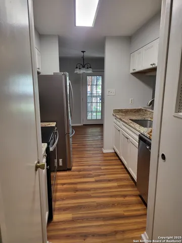 a kitchen with granite countertop a refrigerator a sink and wooden floor