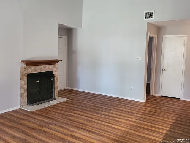 a view of an empty room with wooden floor and a fireplace
