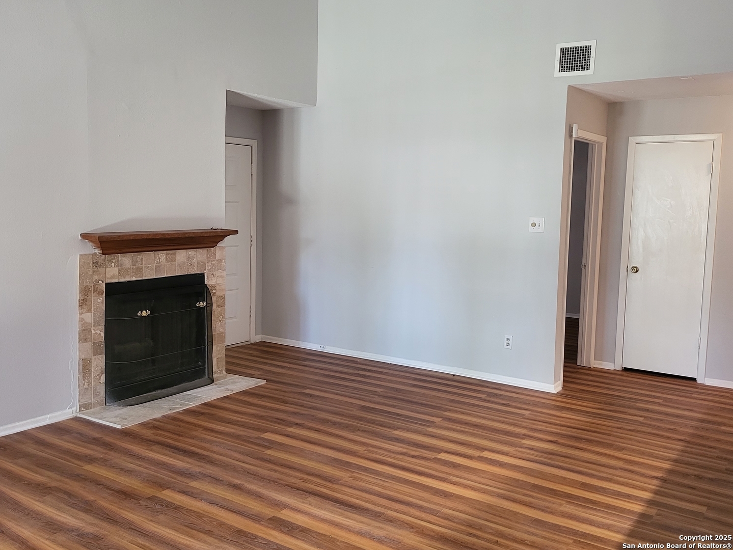 14343 Judson Road, Unit 206 San Antonio, TX 78233 - Photo 8 of 12 a view of an empty room with wooden floor and a fireplace