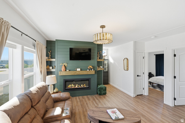 502 West 725 North Logan, UT 84321 - Photo 4 of 25 Living room featuring light wood-type flooring, a fireplace, an accent wall, and wood walls