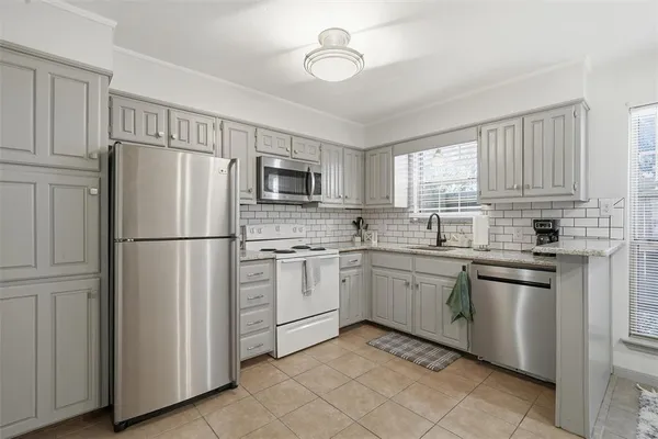 a kitchen with white cabinets stainless steel appliances and a window