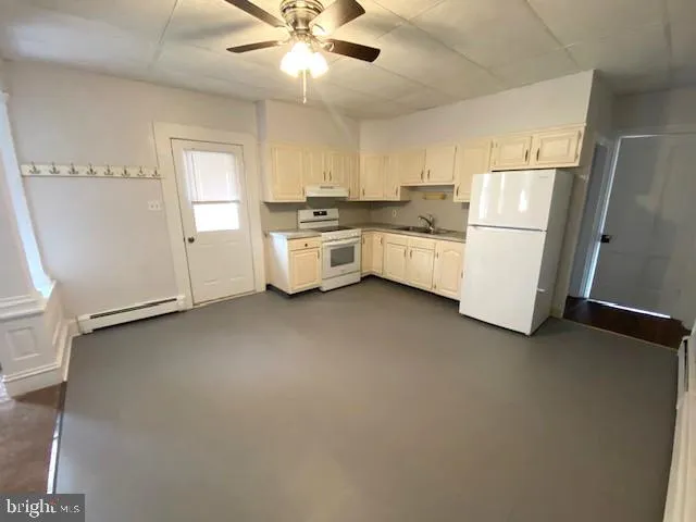 a white kitchen with stainless steel appliances a refrigerator a sink a stove top oven a counter space and cabinets