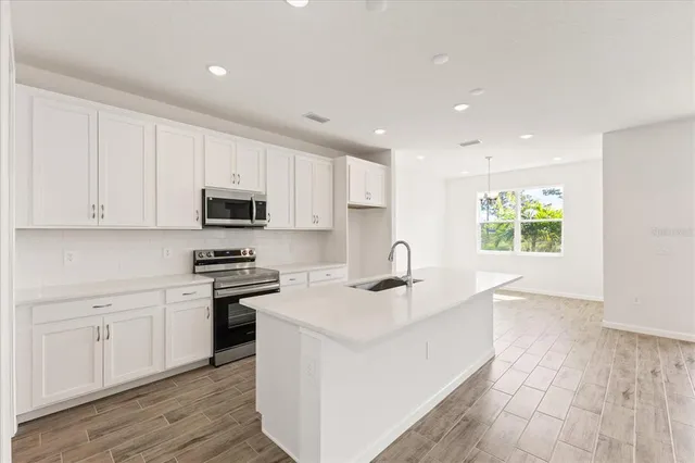 a kitchen with stainless steel appliances granite countertop a sink dishwasher a stove and a refrigerator with wooden floor