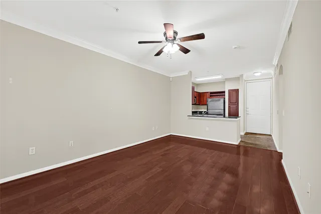 an empty room with wooden floor ceiling fan and windows