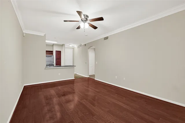 an empty room with wooden floor fan and windows