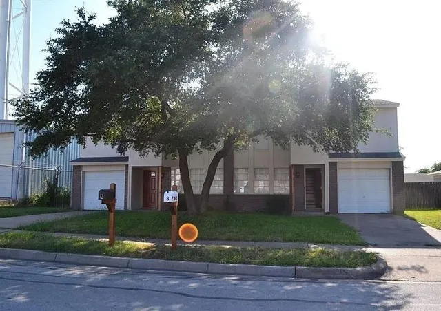a view of a house with a yard and large tree