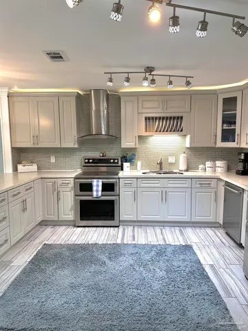 a large white kitchen with stainless steel appliances kitchen island granite countertop a dining table chairs and granite counter tops