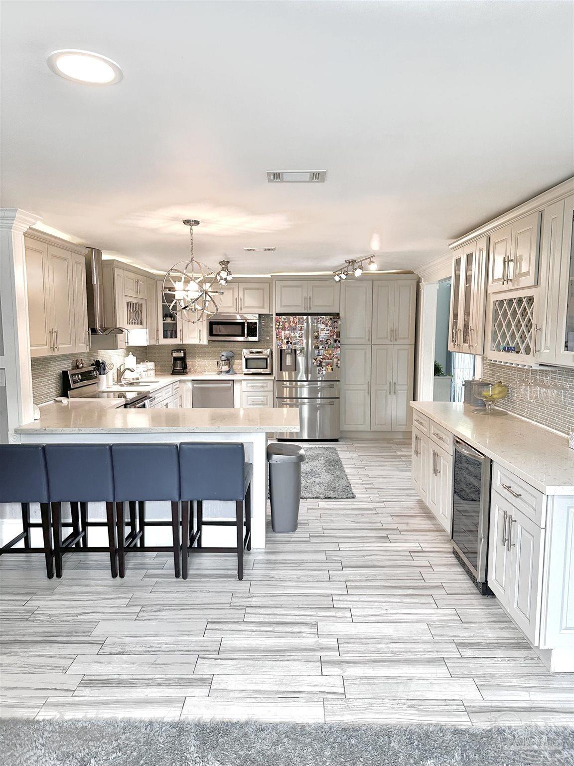 3097 Fayal Drive Pensacola, FL 32526 - Photo 7 of 46 a large white kitchen with stainless steel appliances kitchen island granite countertop a dining table chairs and granite counter tops