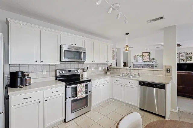 a kitchen with white cabinets appliances and sink