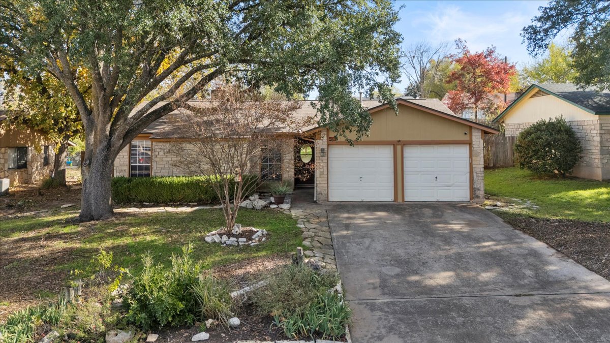 Front of home with concrete driveway, stone siding, a garage, and a front yard
