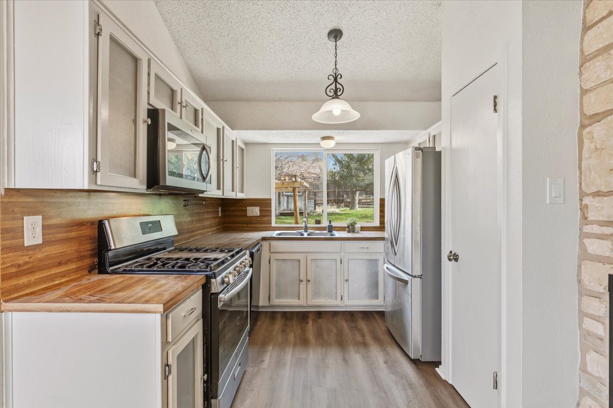 511 Suzzane Road Pflugerville, TX 78660 - Photo 11 of 35 a kitchen with stainless steel appliances a stove a sink and a refrigerator