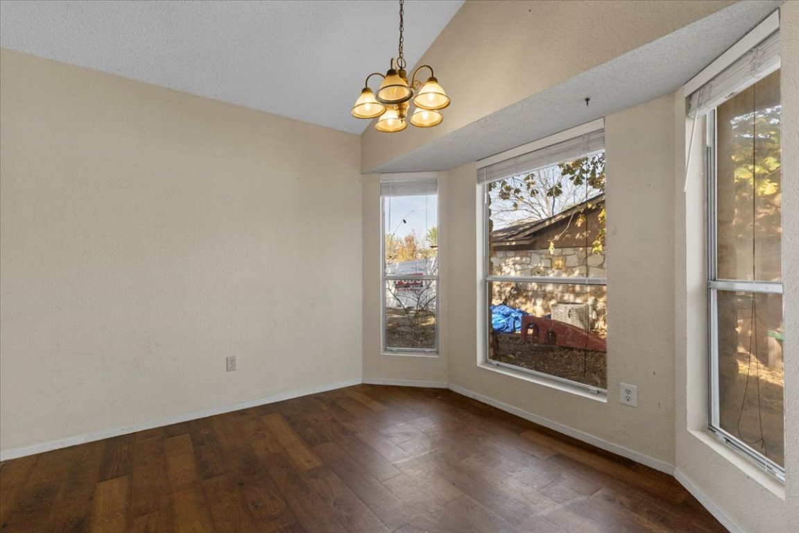 511 Suzzane Road Pflugerville, TX 78660 - Photo 12 of 34 Unfurnished dining area featuring a chandelier, dark wood-style floors, vaulted ceiling, and a textured ceiling