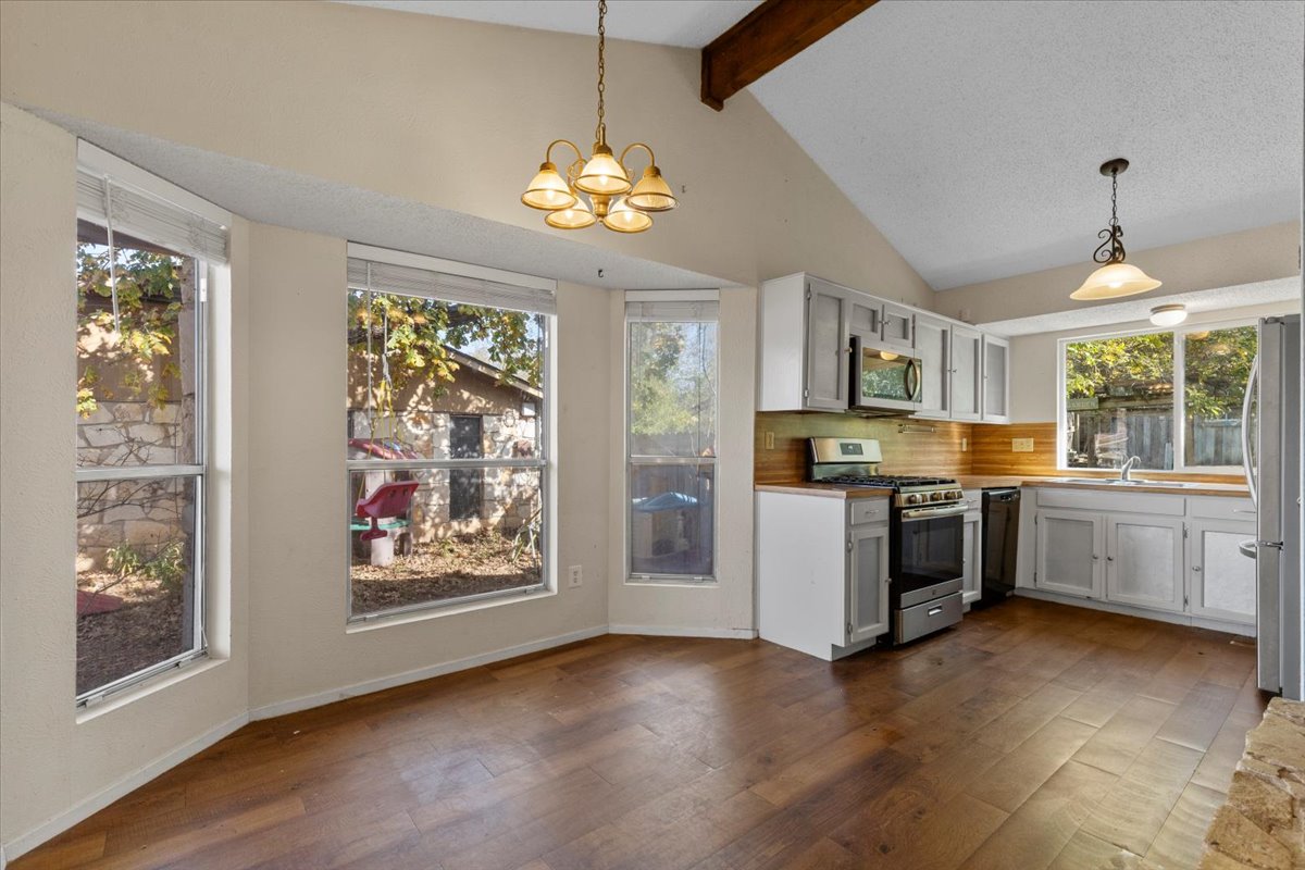 511 Suzzane Road Pflugerville, TX 78660 - Photo 12 of 37 Kitchen with stainless steel appliances, decorative light fixtures, a chandelier, dark wood-style floors, and light countertops