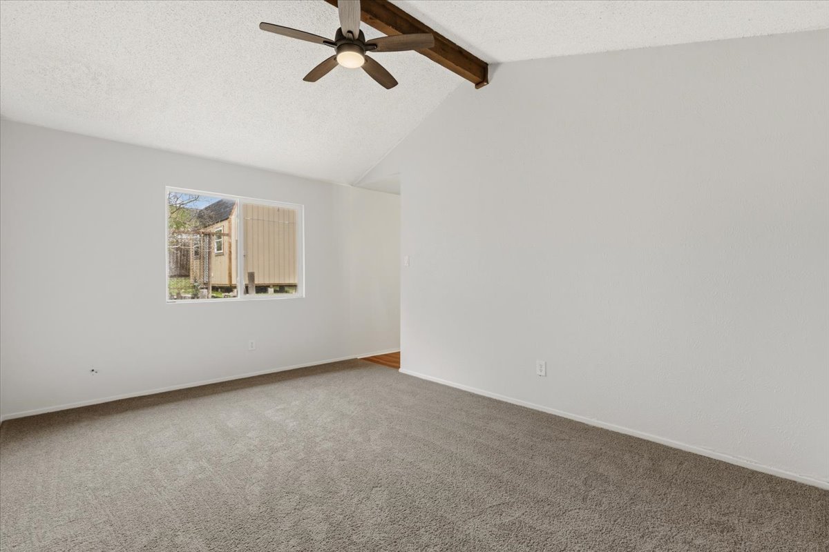 511 Suzzane Road Pflugerville, TX 78660 - Photo 13 of 35 Newly carpeted empty room with a textured ceiling, beam ceiling, and ceiling fan