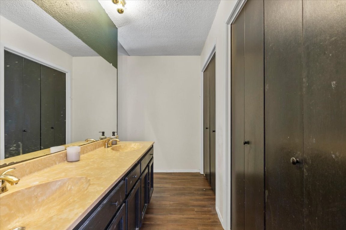 511 Suzzane Road Pflugerville, TX 78660 - Photo 16 of 34 Bathroom featuring double vanity, a textured ceiling, and dark wood-style floors