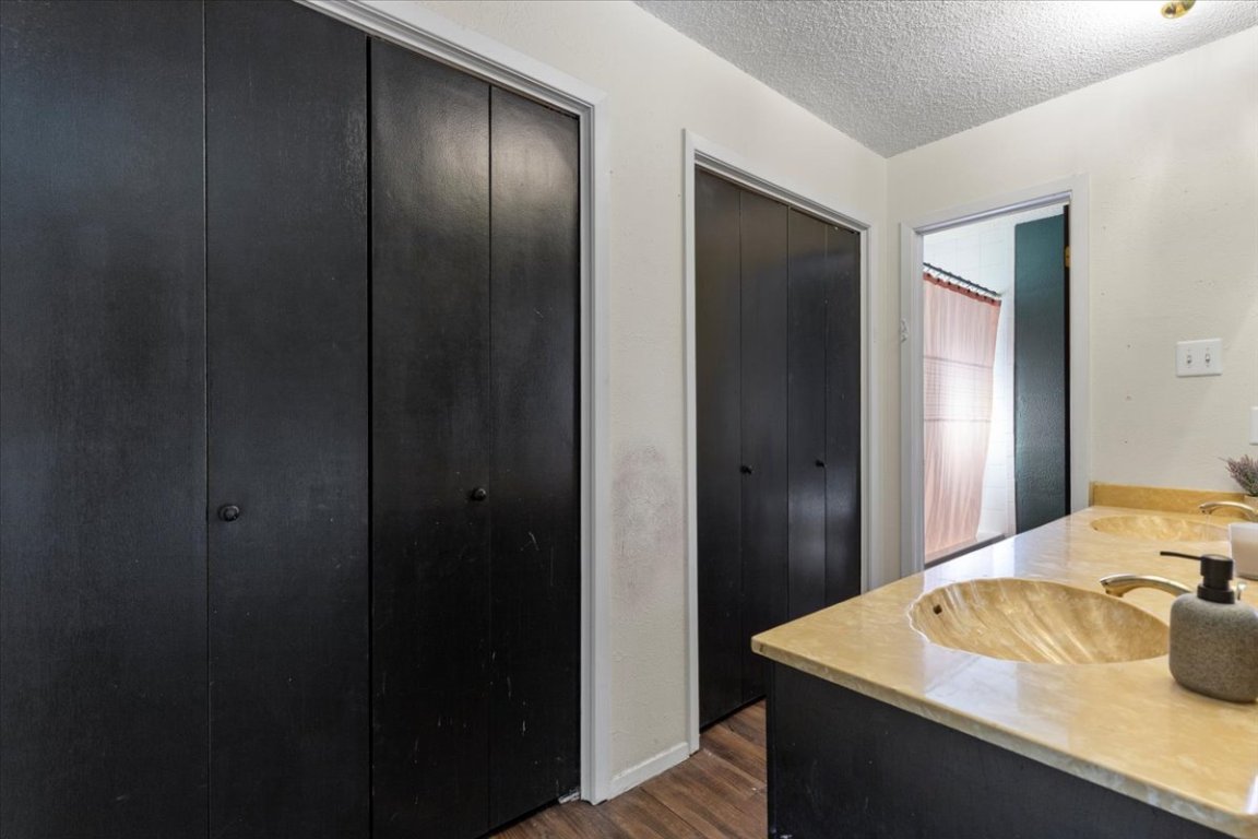 511 Suzzane Road Pflugerville, TX 78660 - Photo 17 of 34 Full bathroom featuring a textured ceiling, a closet, double vanity, dark wood-style floors, and a shower with curtain