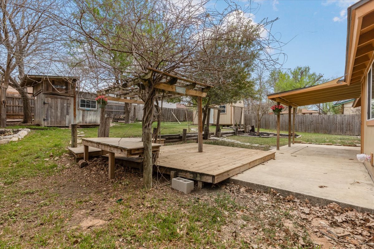 511 Suzzane Road Pflugerville, TX 78660 - Photo 28 of 35 Fenced backyard with a storage unit, a deck, and a patio