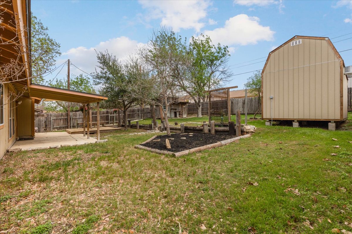 511 Suzzane Road Pflugerville, TX 78660 - Photo 29 of 35 Fenced backyard with a vegetable garden, a patio, and a storage shed