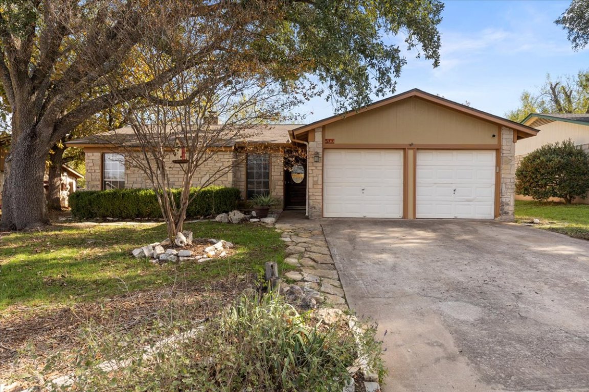 511 Suzzane Road Pflugerville, TX 78660 - Photo 4 of 34 Front of house with driveway, stone siding, a front lawn, and a garage