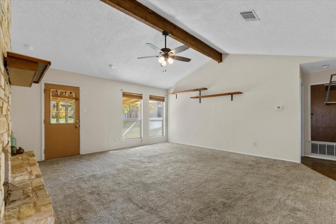 511 Suzzane Road Pflugerville, TX 78660 - Photo 7 of 34 Living room featuring a textured ceiling, light colored carpet, ceiling fan, and a stone fireplace