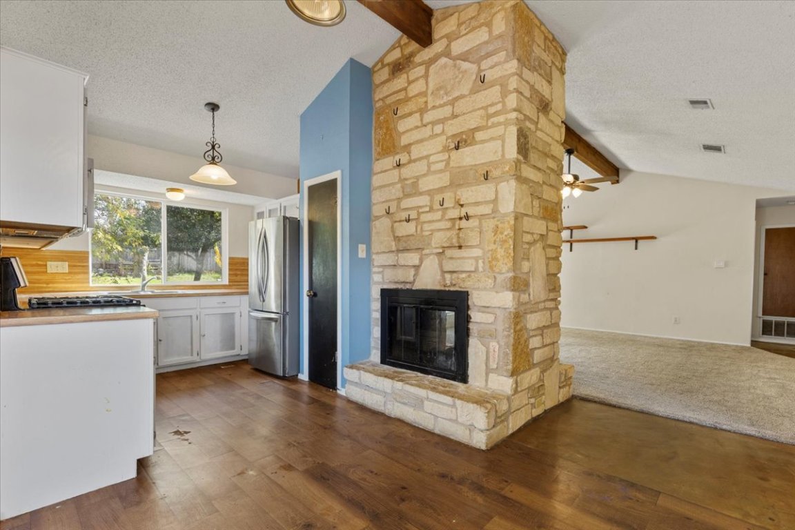 511 Suzzane Road Pflugerville, TX 78660 - Photo 8 of 34 Kitchen featuring white cabinets, a textured ceiling, pendant lighting, stainless steel appliances, and dark wood-style floors