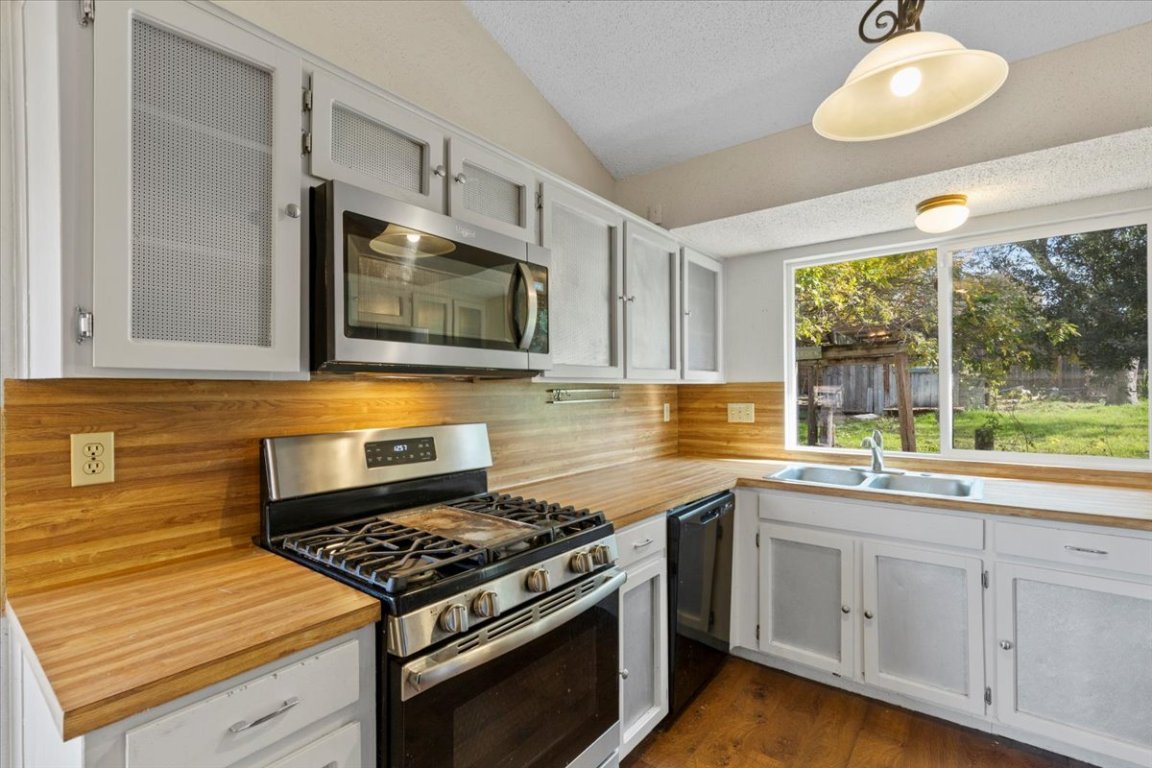 511 Suzzane Road Pflugerville, TX 78660 - Photo 9 of 34 Kitchen with appliances with stainless steel finishes, white cabinetry, light countertops, decorative light fixtures, and a textured ceiling
