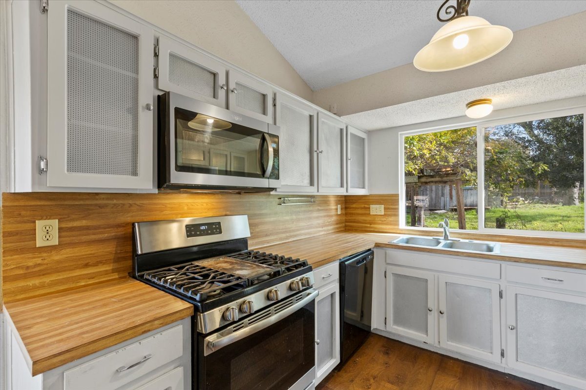 511 Suzzane Road Pflugerville, TX 78660 - Photo 9 of 37 Kitchen with appliances with stainless steel finishes, white cabinetry, light countertops, decorative light fixtures, and a textured ceiling