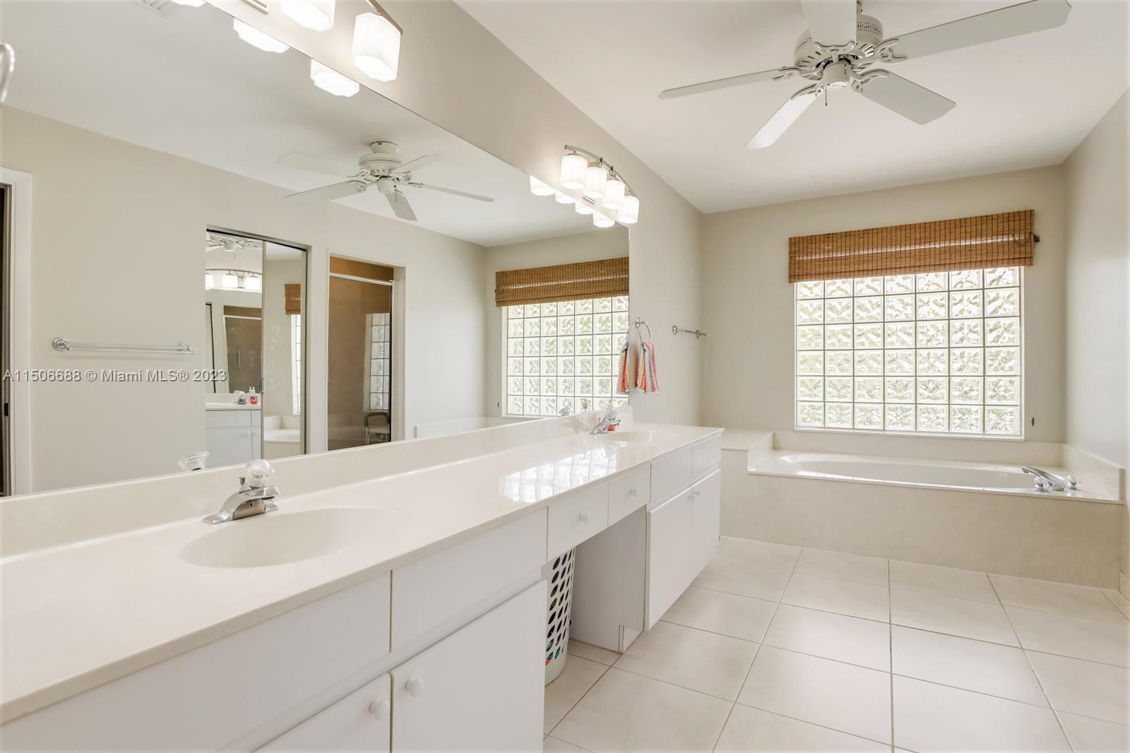 7289 Shell Ridge Terrace Lake Worth, FL 33467 - Photo 32 of 55 a bathroom with a granite countertop sink a large mirror and a bathtub next to a window