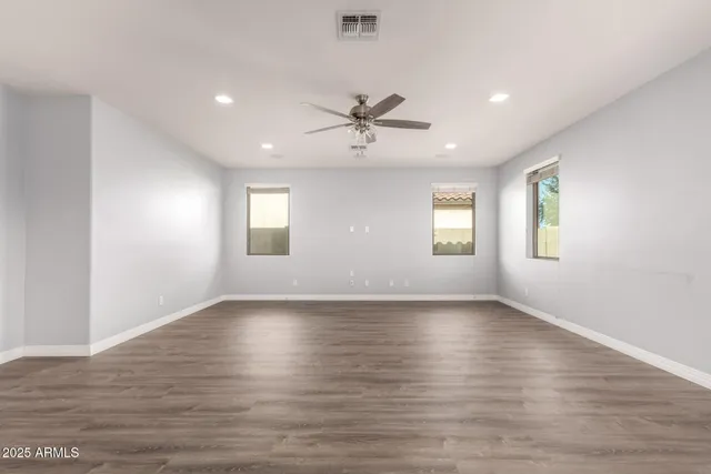 a view of an empty room with window and wooden floor