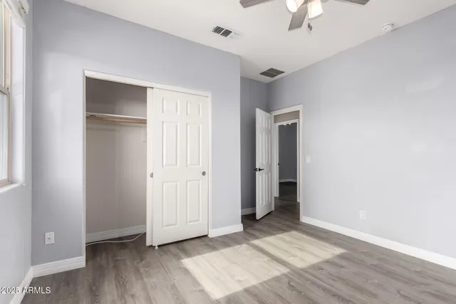 a view of an empty room with window and wooden floor