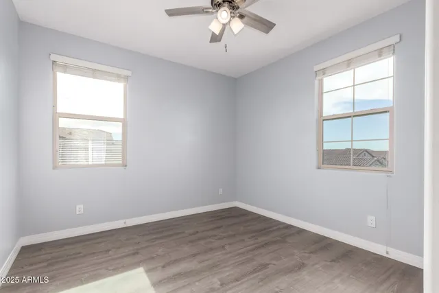 an empty room with wooden floor chandelier and windows