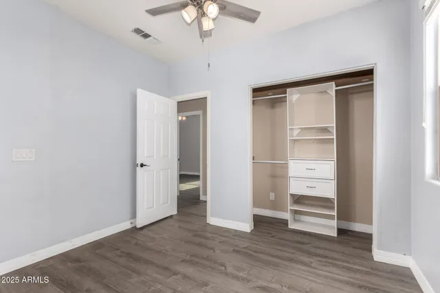 an empty room with wooden floor closet and windows