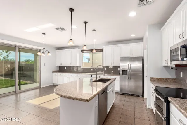 a kitchen with stainless steel appliances granite countertop a sink a stove a refrigerator and a granite counter tops