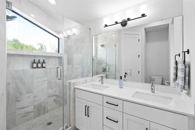 a bathroom with a double vanity sink mirror and shower
