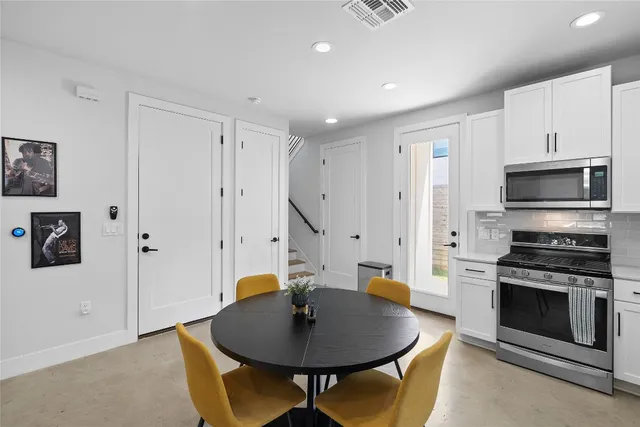 a living room with stainless steel appliances a dining table and a fireplace