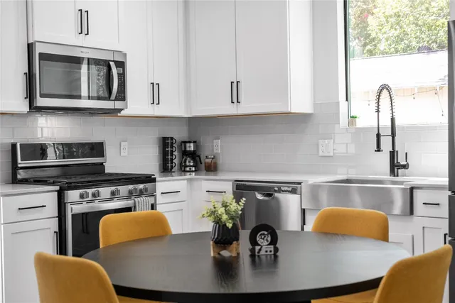 a kitchen with stainless steel appliances granite countertop a stove a sink dishwasher a microwave oven with a dining table and chairs