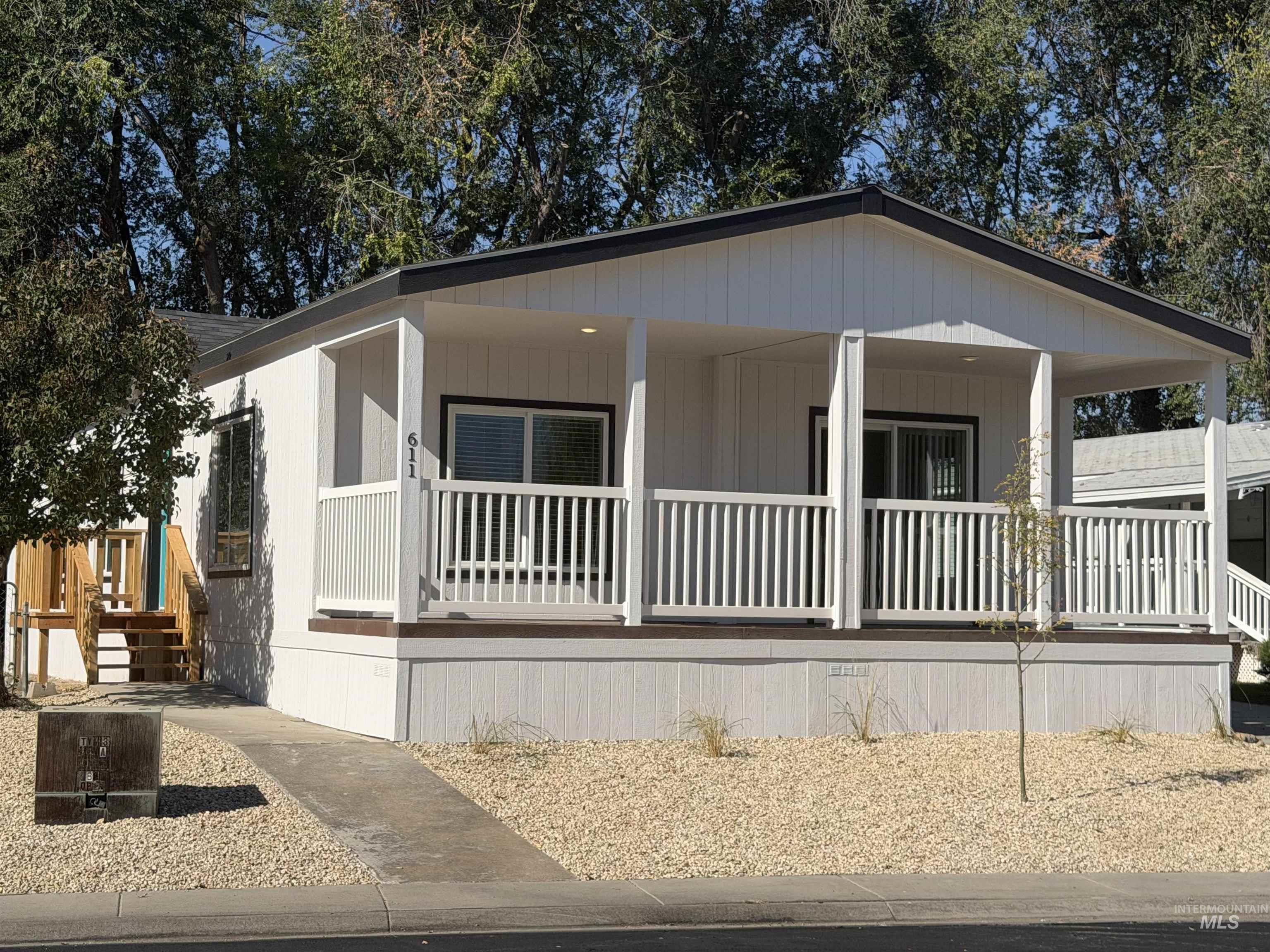 611 North Timathy Road Boise, ID 83713 - Photo 1 of 28 White vertical siding exterior with a covered porch, white railing, dark trim, and a gravel front yard
