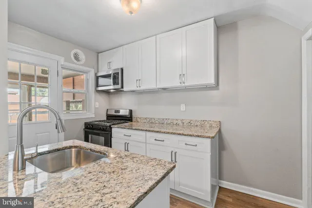 a kitchen with granite countertop a sink stove and cabinets