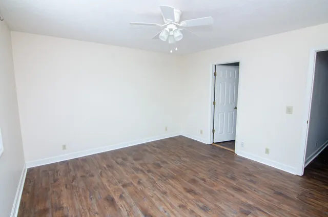 an empty room with wooden floor and fan