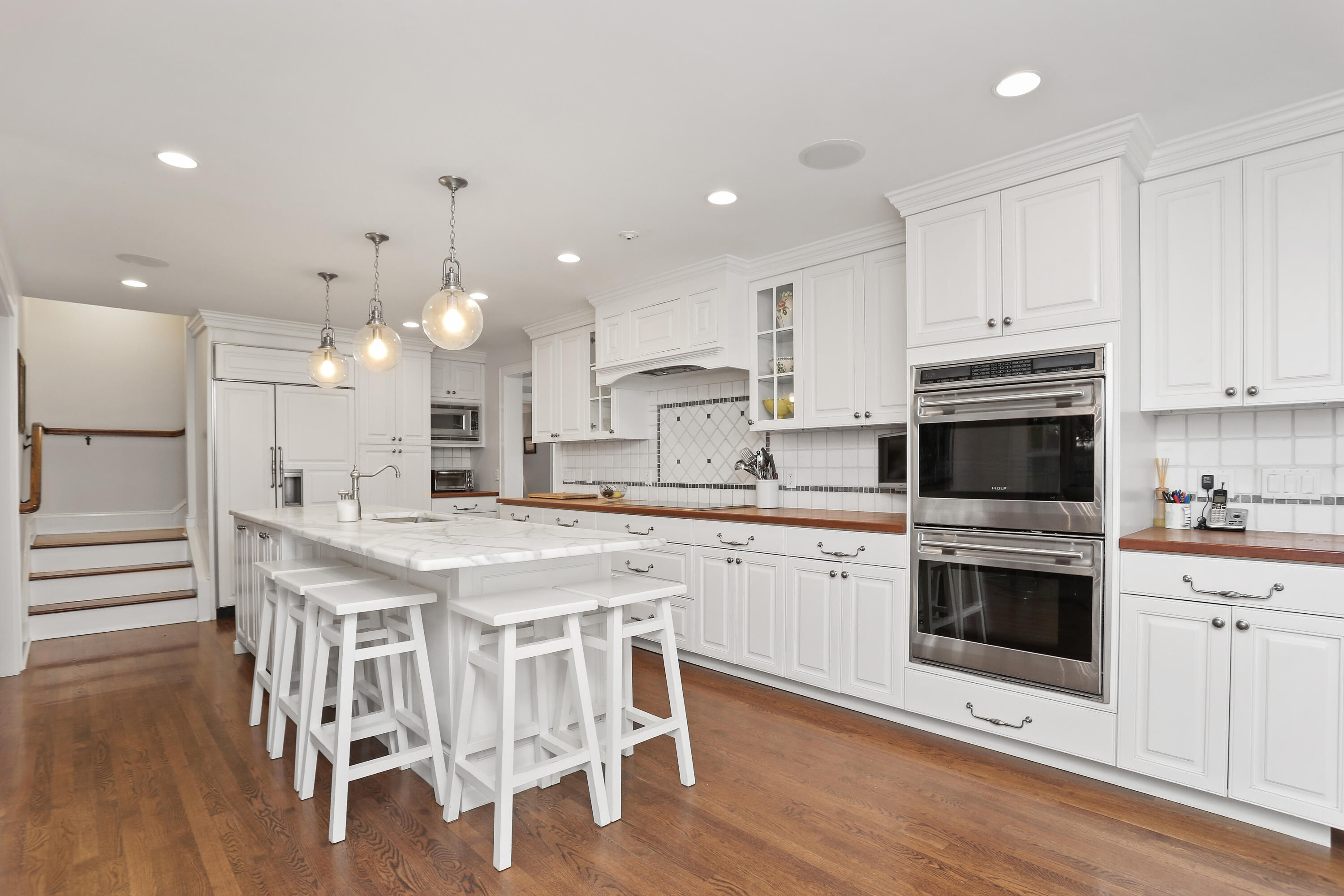8 Beach Drive Darien, CT 06820 - Photo 11 of 27 a kitchen with stainless steel appliances granite countertop a stove top oven a sink dishwasher a refrigerator and a dining table with wooden floor