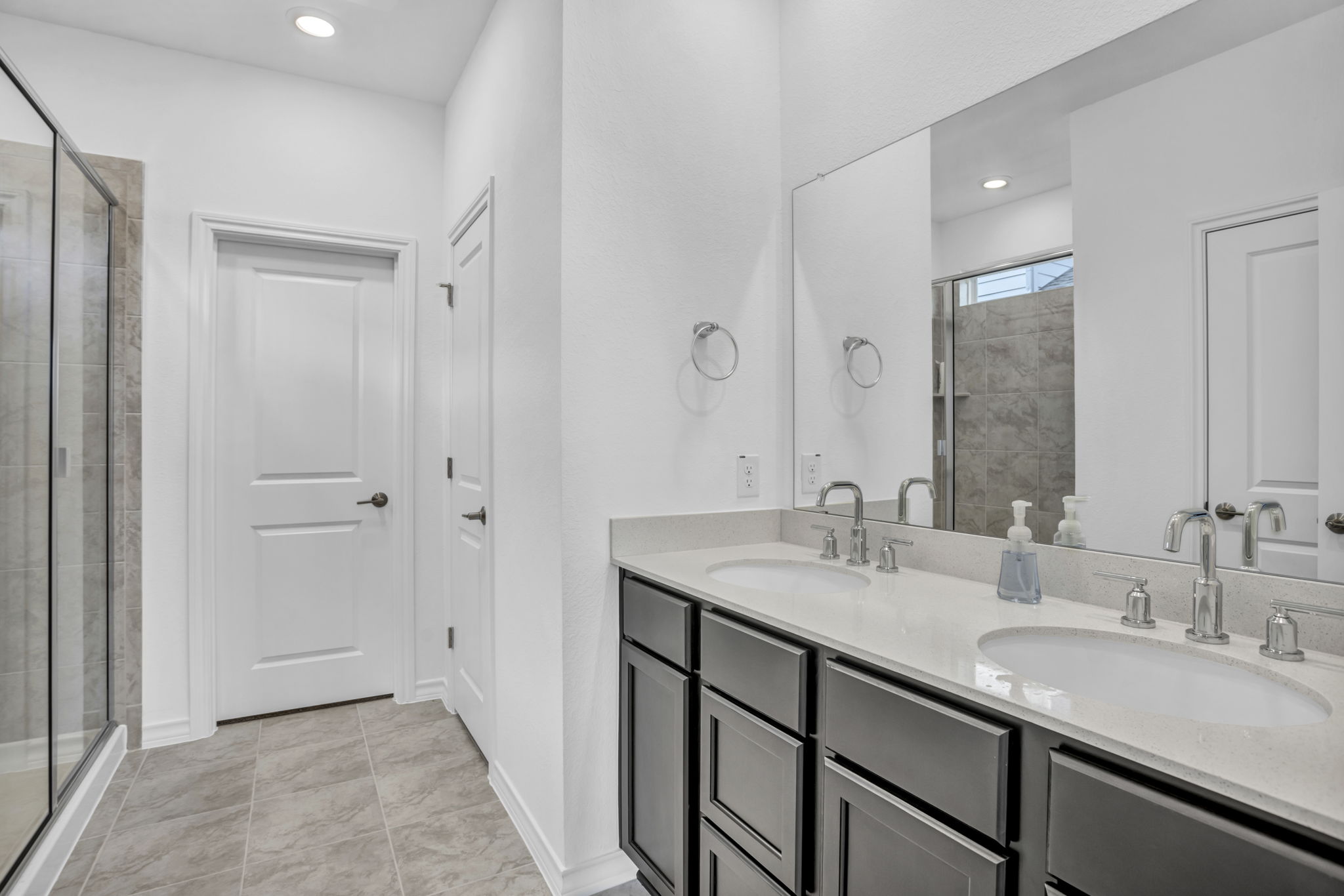 131 Adeline Road Hutto, TX 78634 - Photo 23 of 30 Dual vanity with bright quartz countertops and a spacious glass-enclosed shower.