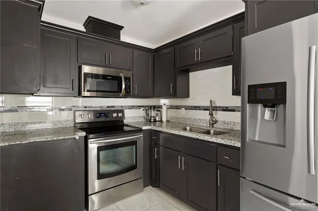 a kitchen with stainless steel appliances granite countertop a stove a sink and a refrigerator