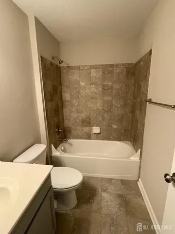 a bathroom with a bathtub shower sink mirror vanity and toilet