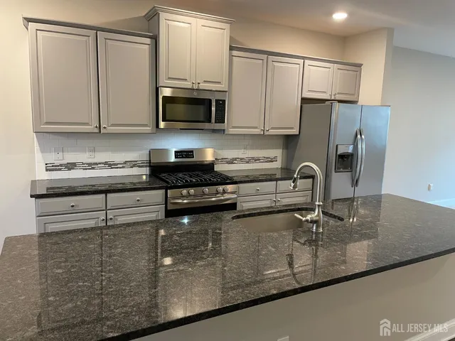 a kitchen with stainless steel appliances granite countertop a sink a stove a refrigerator a center island and a refrigerator