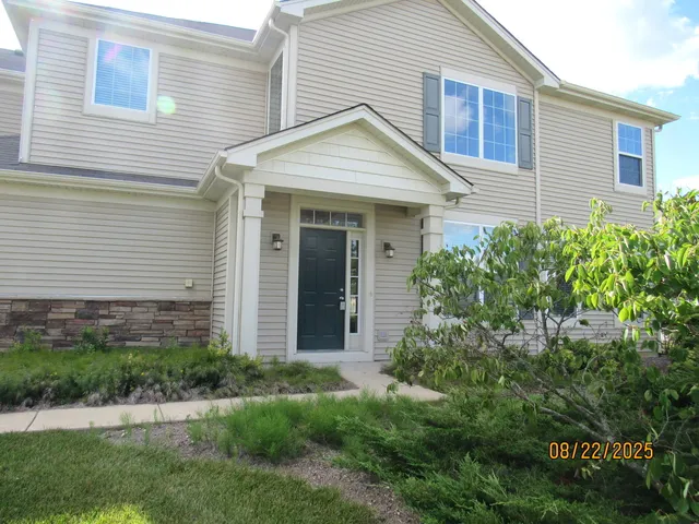 a view of a house with brick walls and a yard with plants