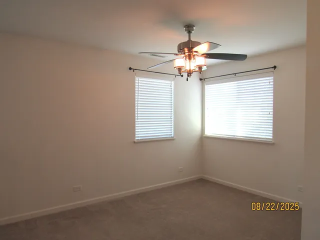 en empty room with windows and chandelier fan
