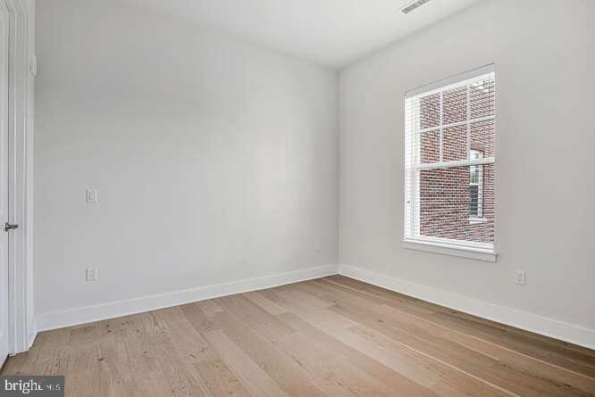 6803 Cameron Drive Northwest, Unit 314 Washington, DC 20012 - Photo 4 of 25 an empty room with wooden floor and windows