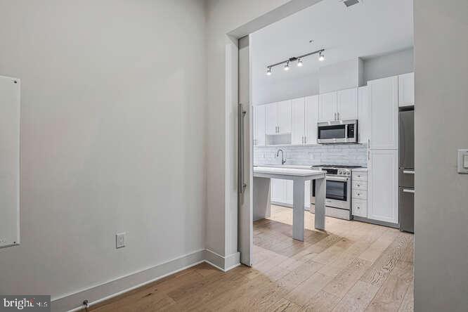 6803 Cameron Drive Northwest, Unit 314 Washington, DC 20012 - Photo 7 of 25 a open kitchen with white cabinets and stainless steel appliances