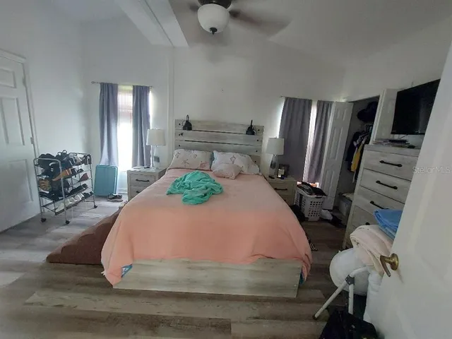 a bedroom with a bed dresser and wooden floor