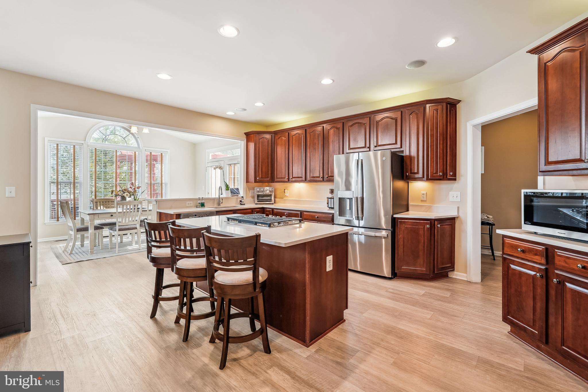 42801 Ridgeway Drive Broadlands, VA 20148 - Photo 8 of 40 a kitchen with a refrigerator a stove top oven a sink dishwasher and chairs with wooden floor